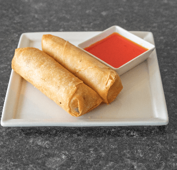Two golden-brown spring rolls with dipping sauce on a white plate.