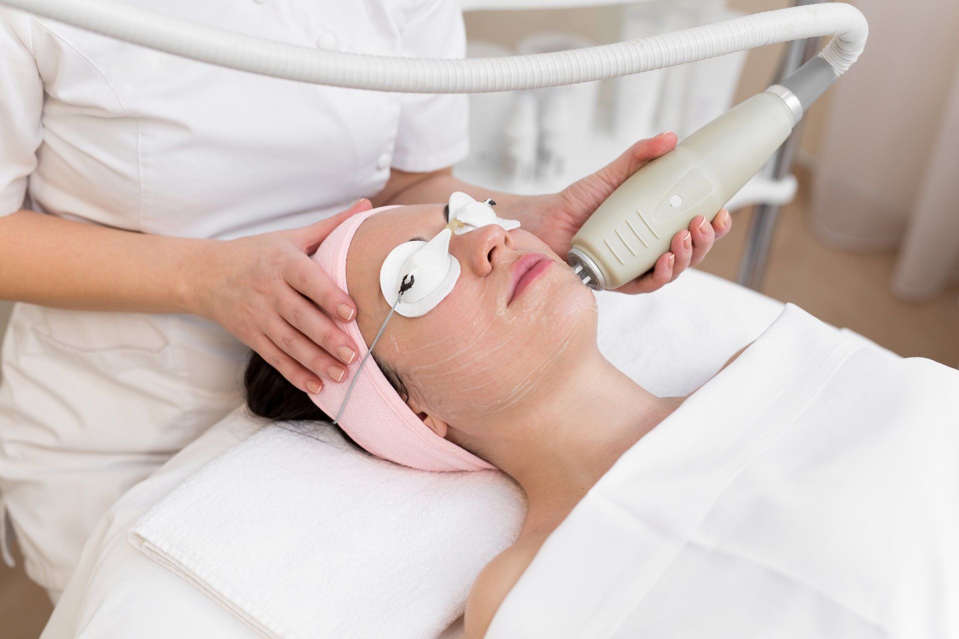 Medical aesthetician performs facial treatment on client who is wearing protective googles