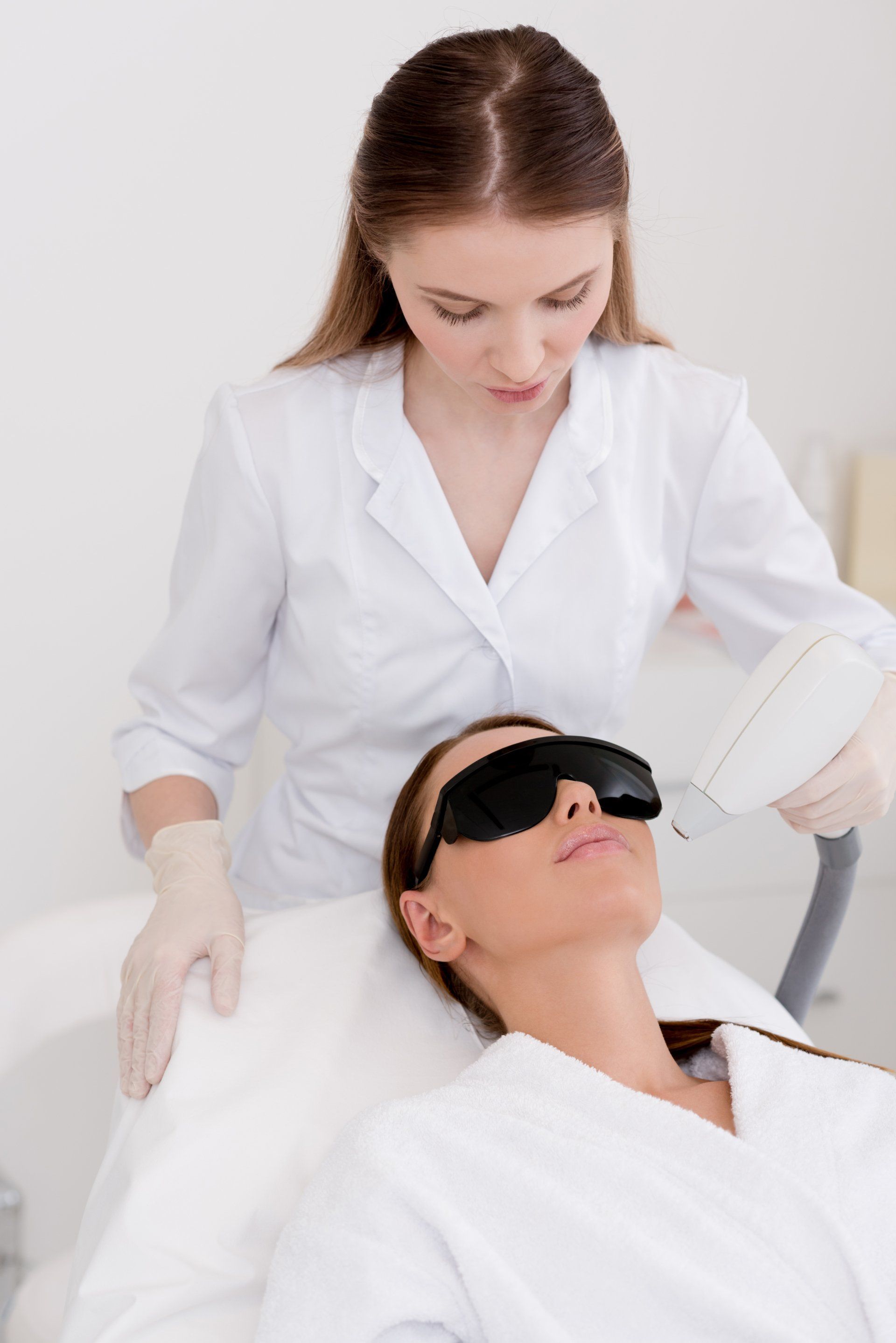 Woman getting laser hair removal treatment on face
