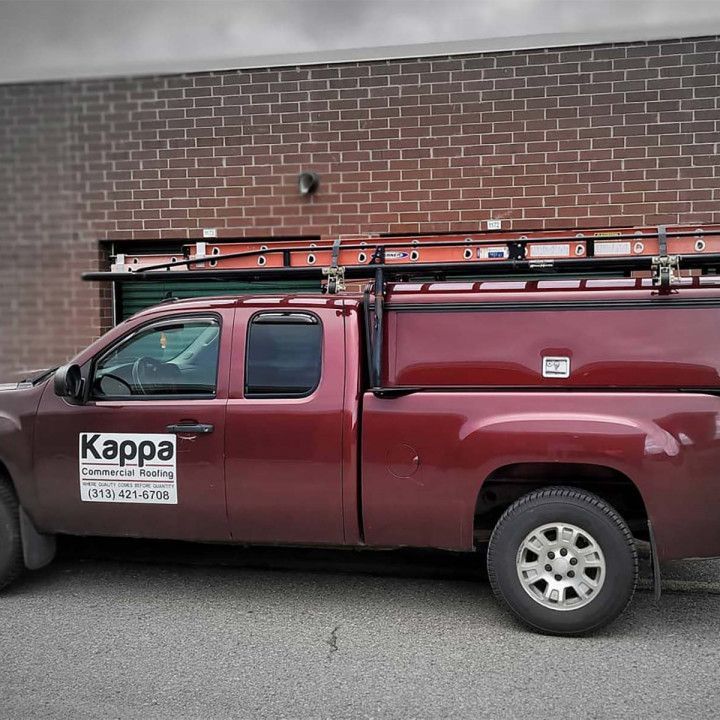 A red kappa truck is parked in front of a brick building