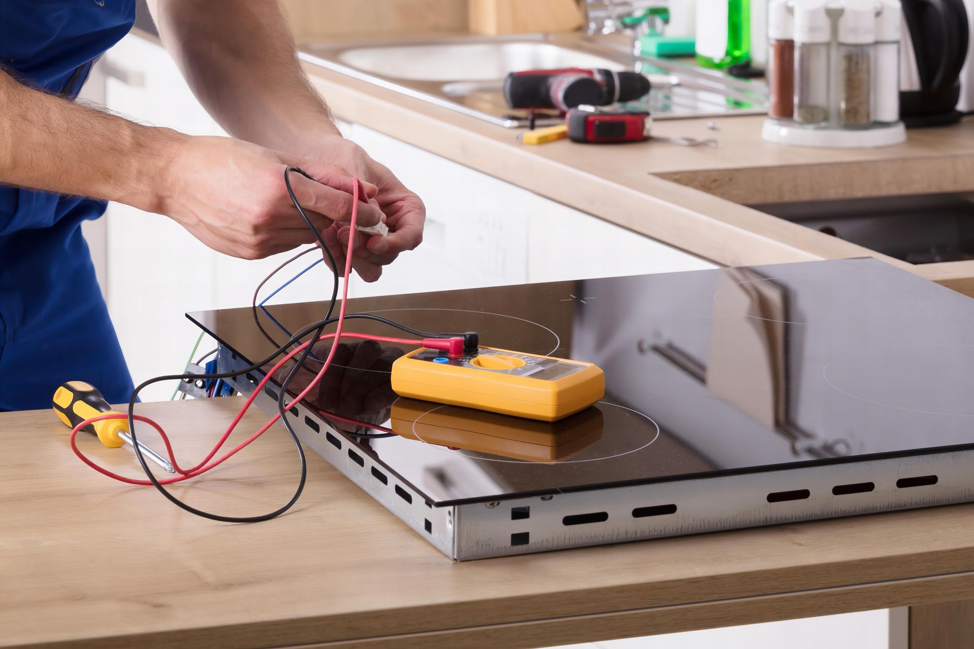 Technician repairing induction stove in kitchen. Technician repairing induction stove in kitchen.