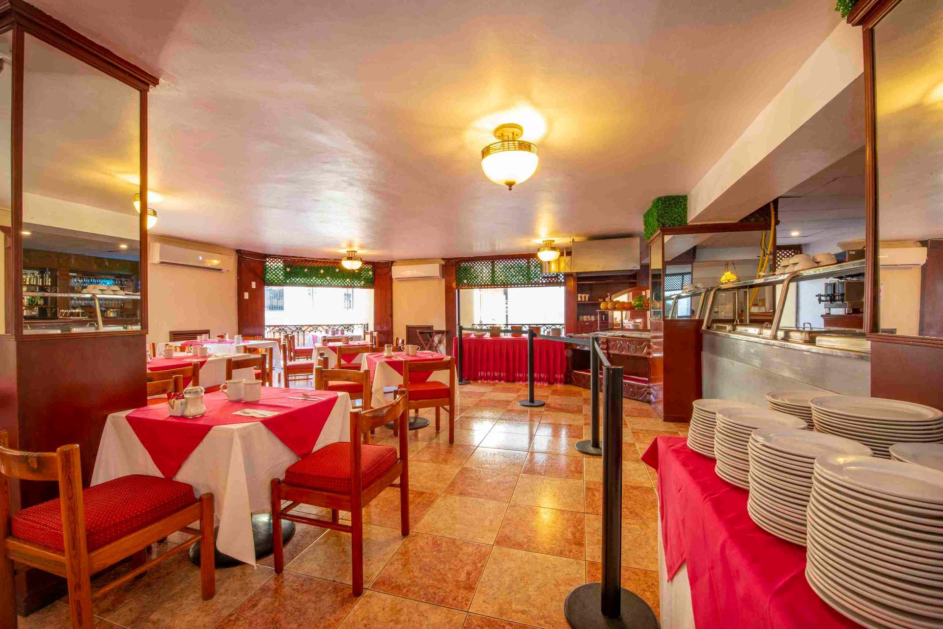 A restaurant with tables and chairs and plates on the counter.
