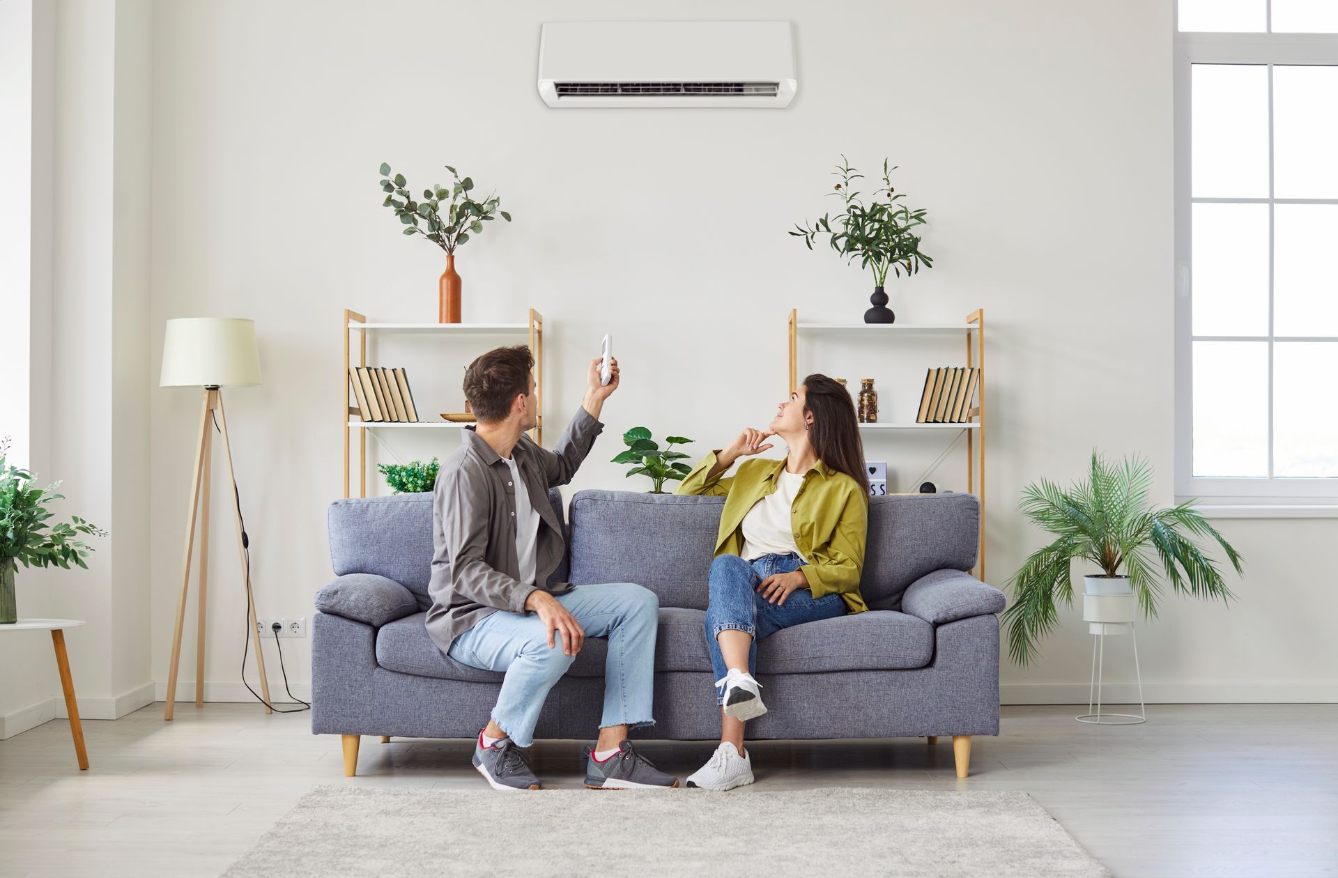 A relaxed couple is seated on a couch while enjoying their air conditioning system at home.