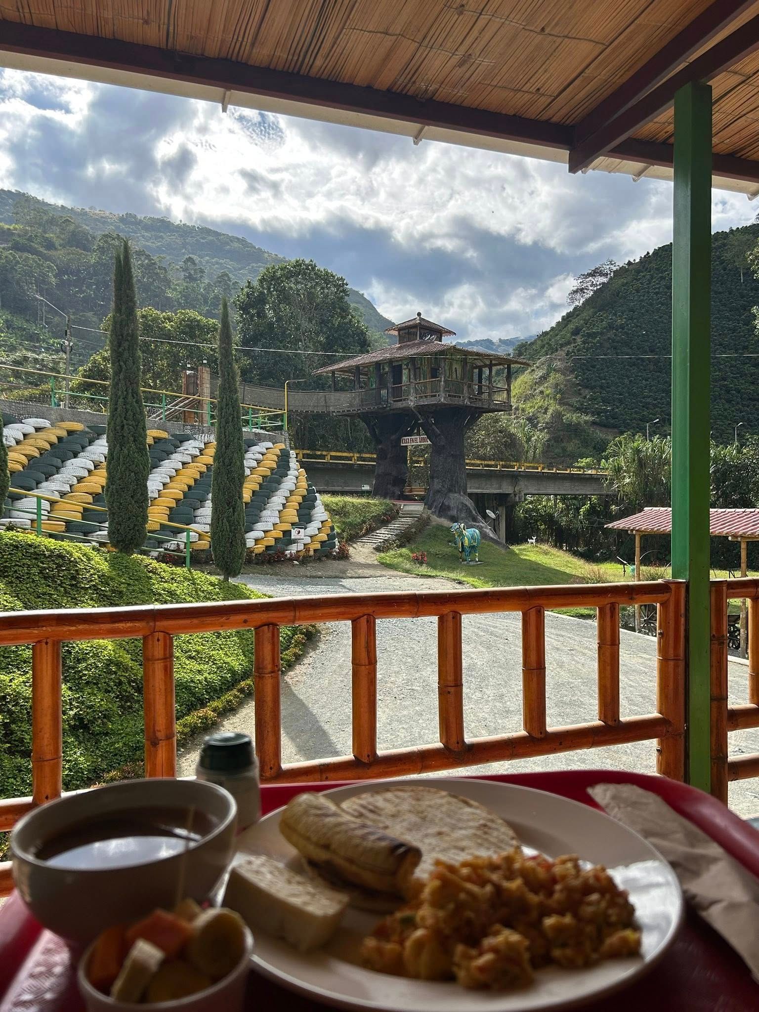 Plato de desayuno con vista panorámica: huevos, pan y sopa en una mesa con vista a un valle.
