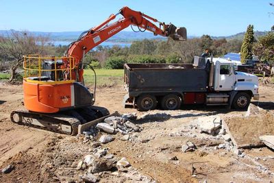 orange excavator dumping debris in truck