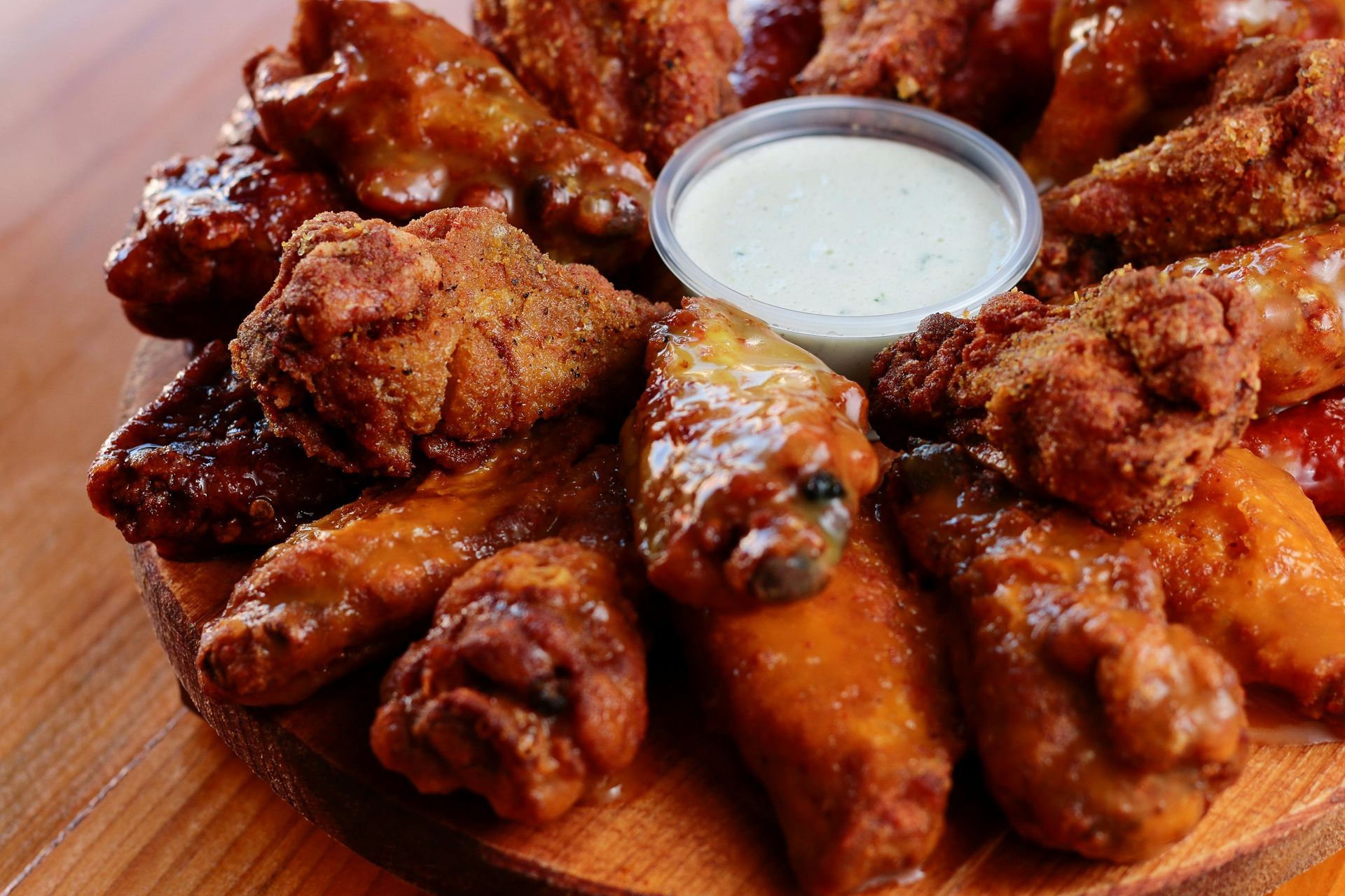 A wooden cutting board topped with chicken wings and dipping sauce.