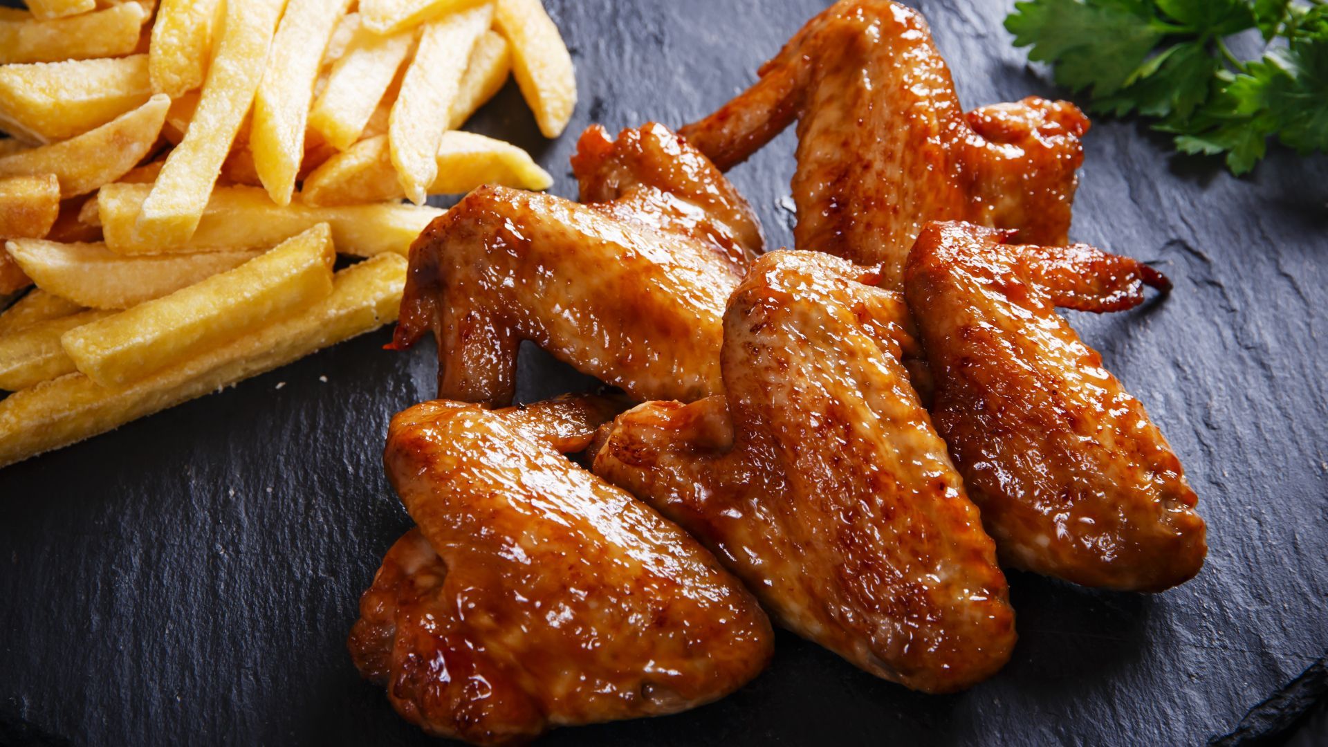 A plate of chicken wings and french fries on a table.