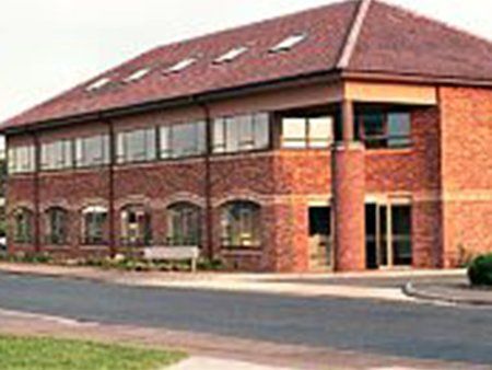 Two-storey red brick building with parking area in front