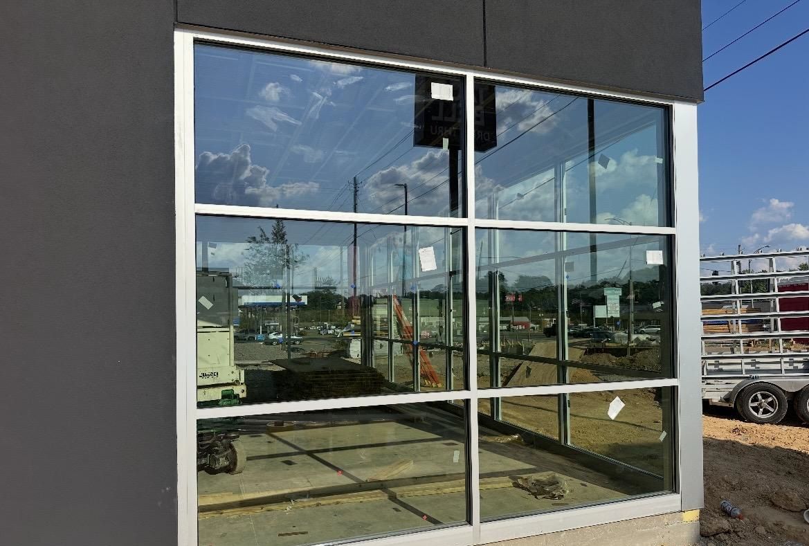 Large glass windows with silver frames reflect the sky and surrounding construction.