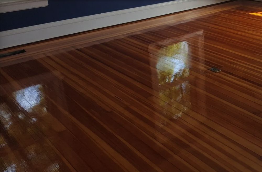 Shiny, reflective hardwood floor with window reflections.