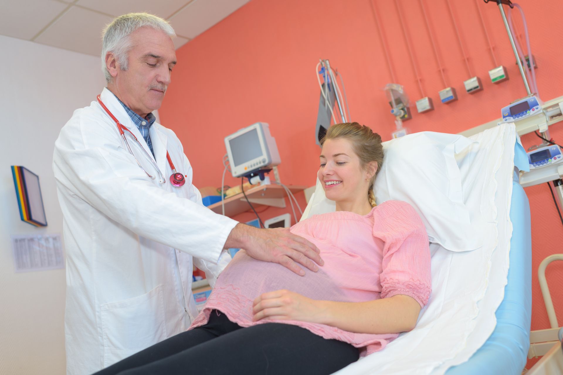 A gynecologist examining a pregnant patient in a consultation room.