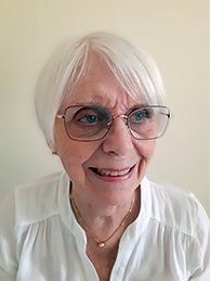 Maureen Willetts wearing glasses and a white shirt is smiling.