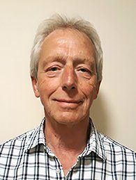 A man in a plaid shirt is smiling for the camera.