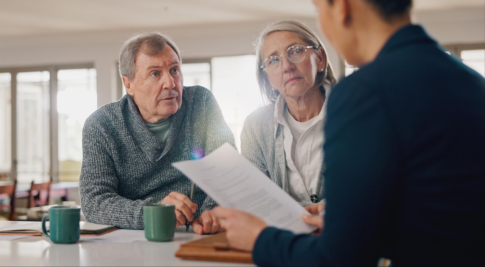 Two people review a document with a counselor at a table in a bright office