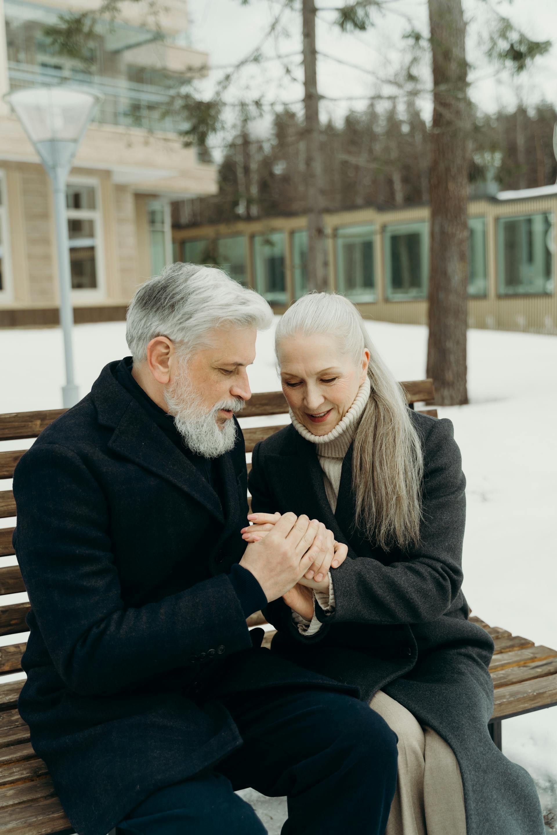 A man and a woman are sitting on the floor in a gym . the woman is bandaging the man 's ankle.