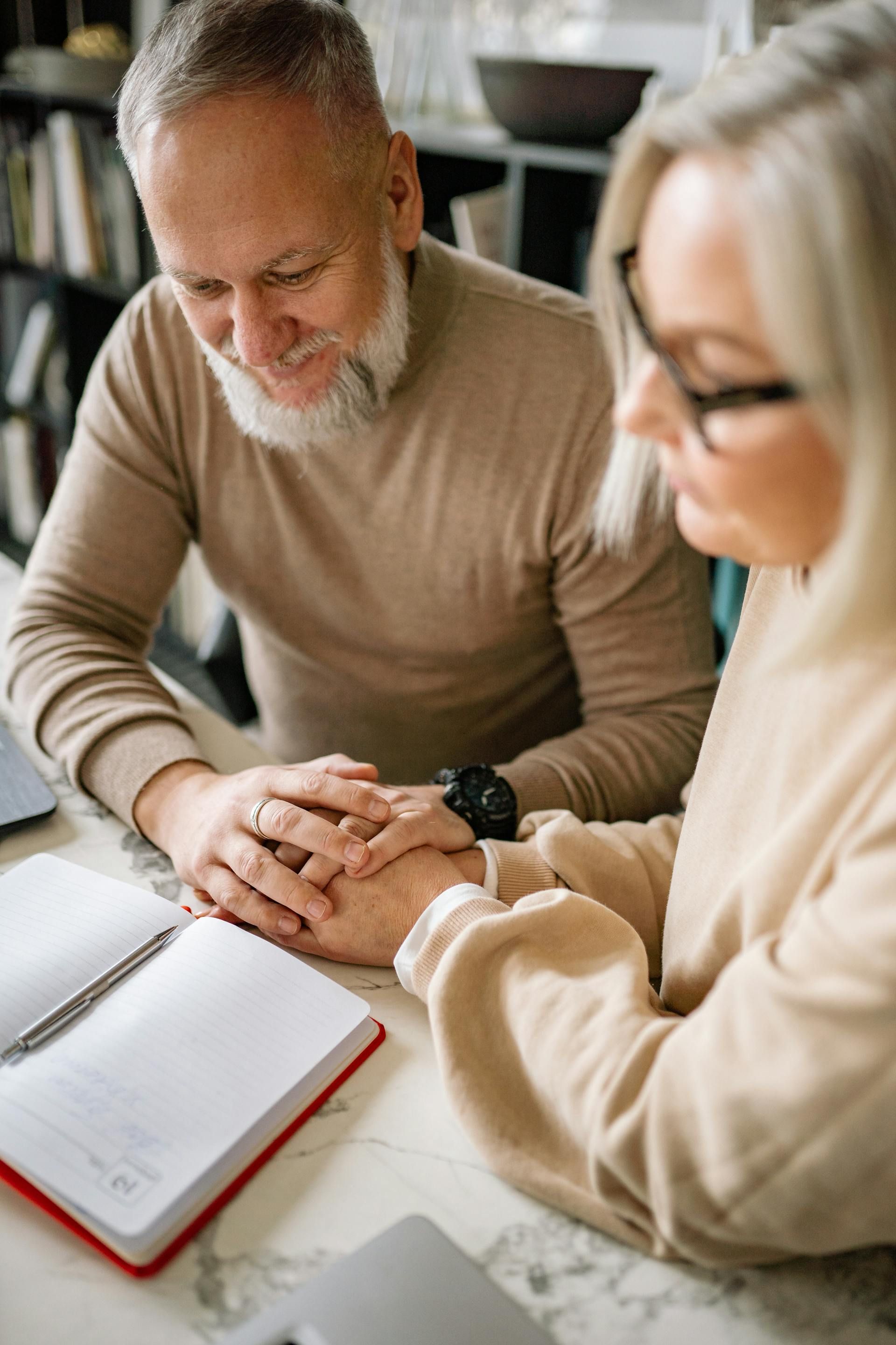 A man and a woman are sitting on the floor in a gym . the woman is bandaging the man 's ankle.