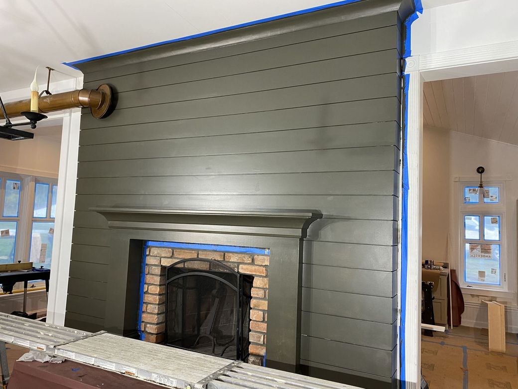 A fireplace is being painted in a living room.