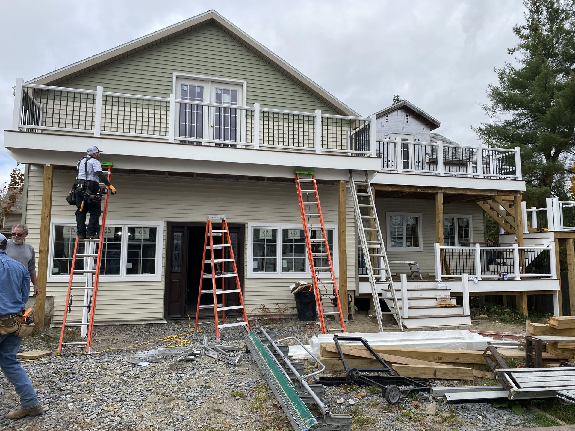 A man is standing on a ladder in front of a house under construction.