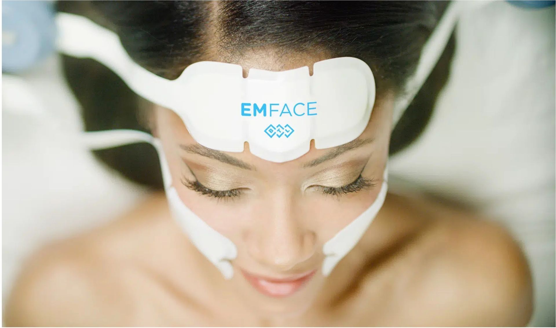 Woman undergoing Emface treatment with applicators, showcasing skin and muscle improvement statistics.