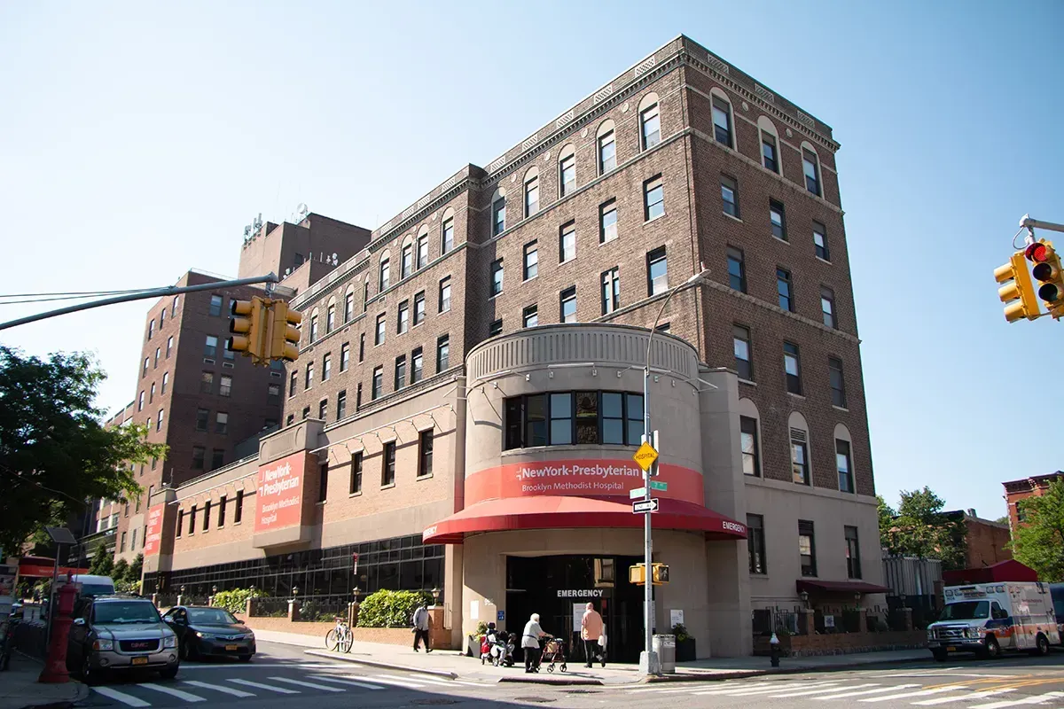 A large building with a red awning is on the corner of a city street.