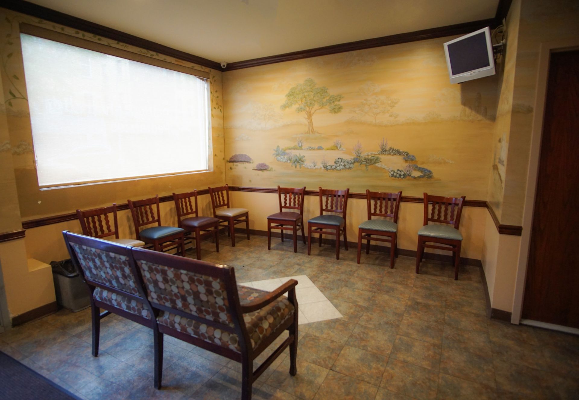 A waiting room with chairs and a television on the wall.