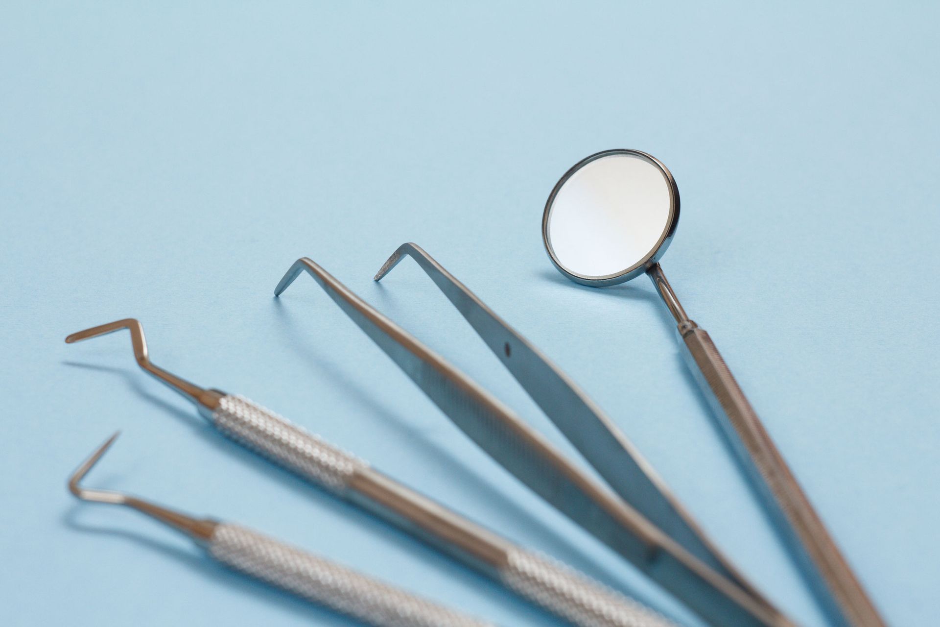 A set of dental instruments on a blue surface.