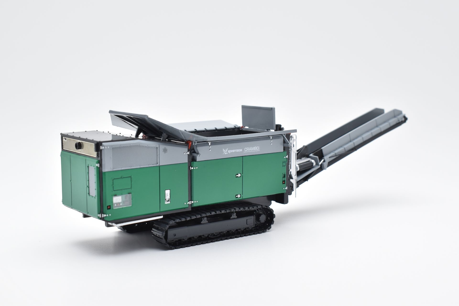 Groene en grijze mobiele breker op rupsbanden op een witte achtergrond.