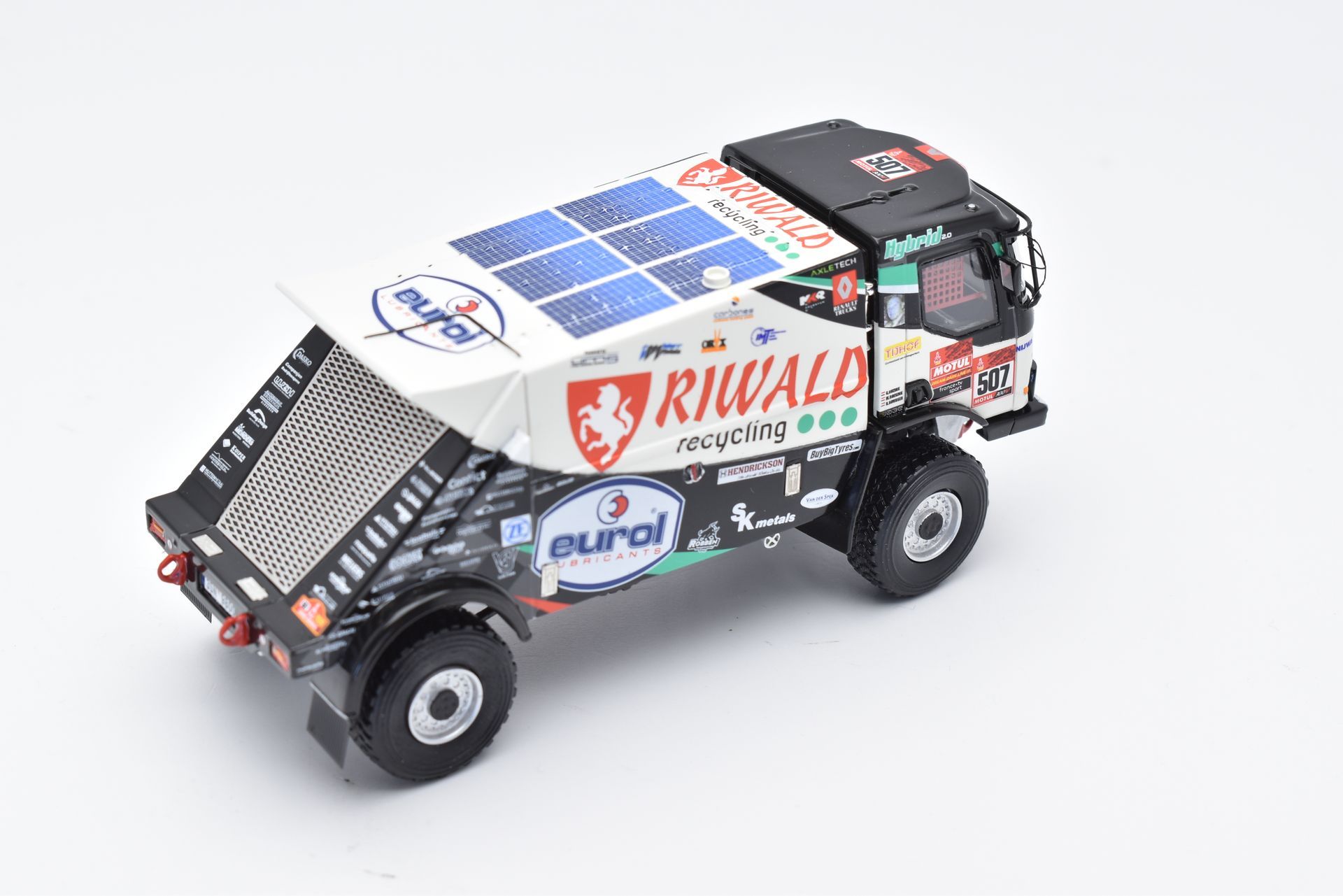 Schaalmodel van een rallytruck met zonnepanelen op het dak, met teambranding en sponsoren op een witte achtergrond.