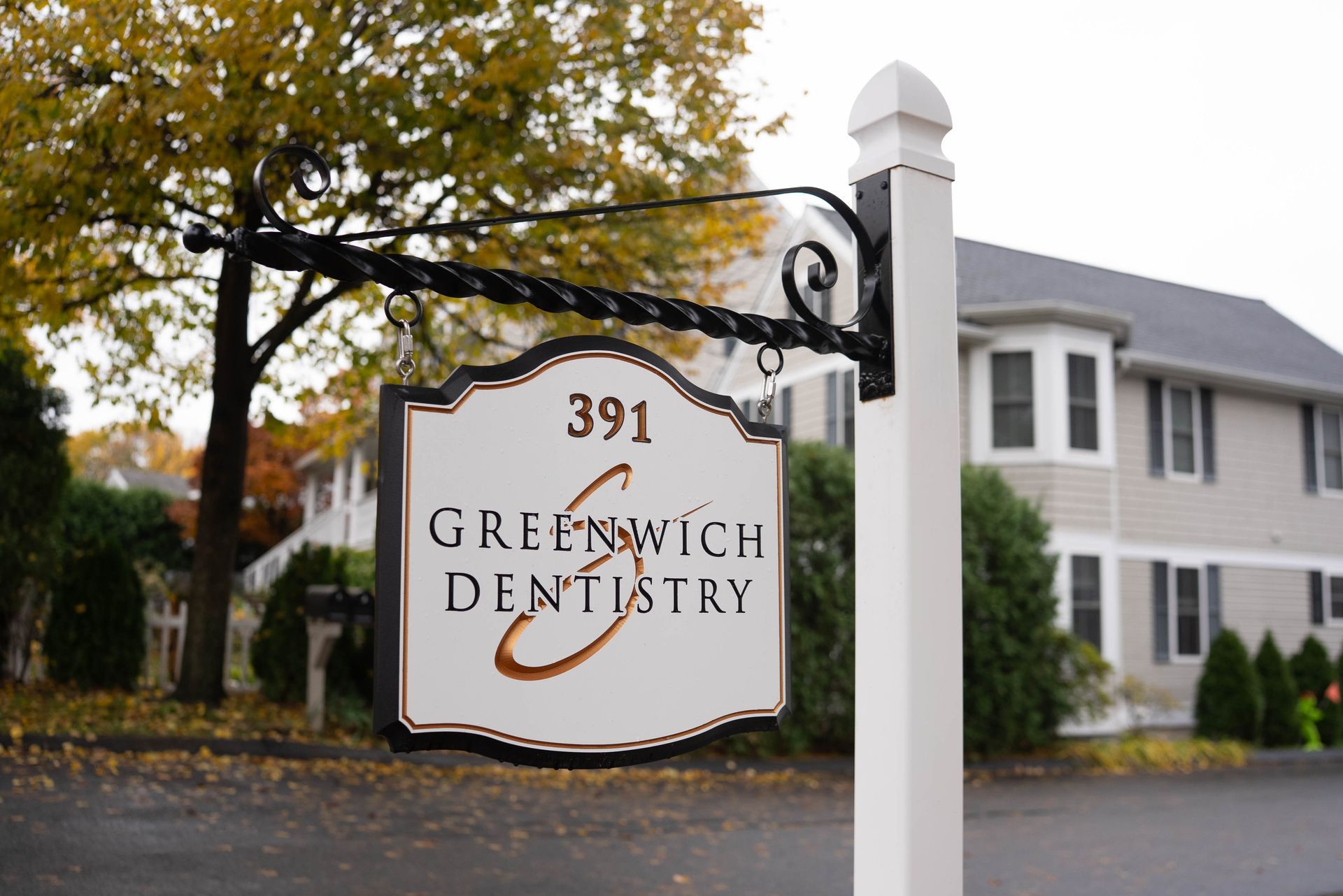 A sign for greenwich dentistry hangs from the side of a building