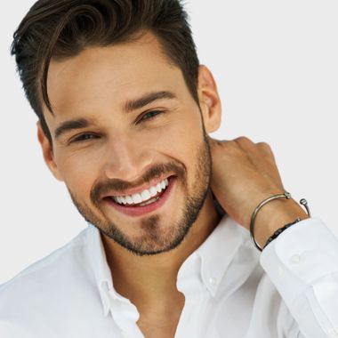 A man with a beard wearing a white shirt is smiling