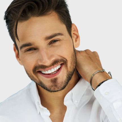 A man with a beard wearing a white shirt is smiling
