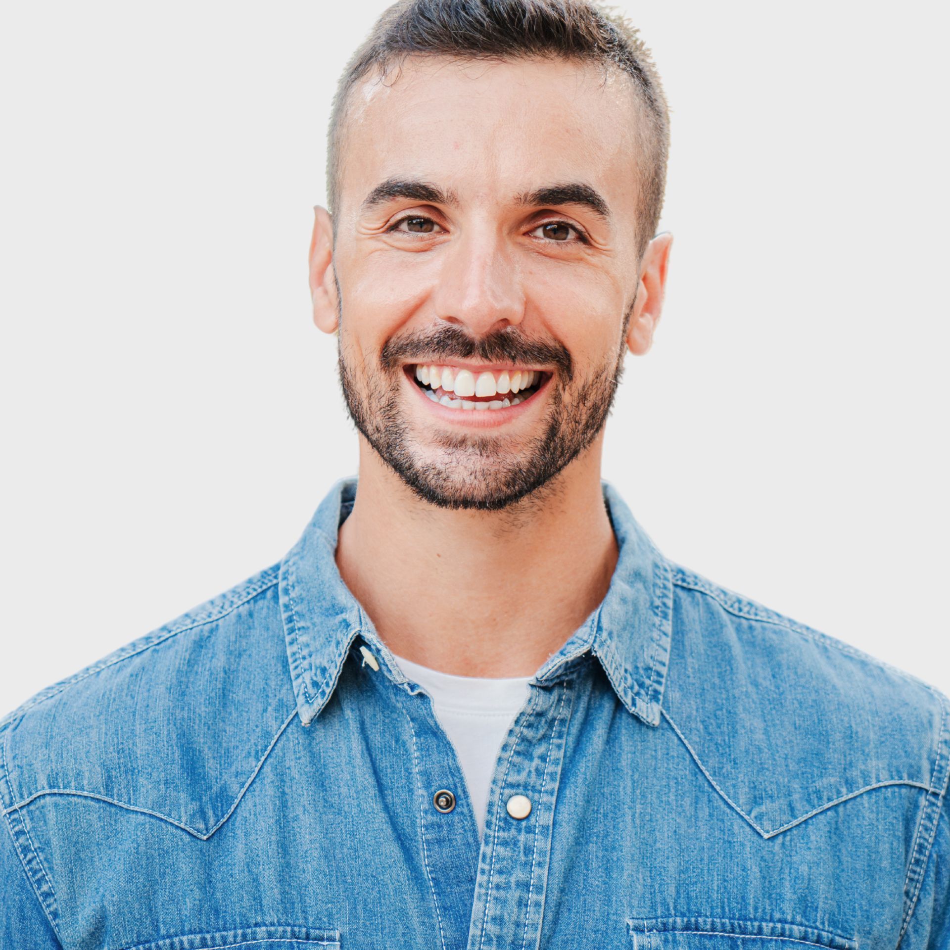A man with a beard is wearing a denim shirt and smiling