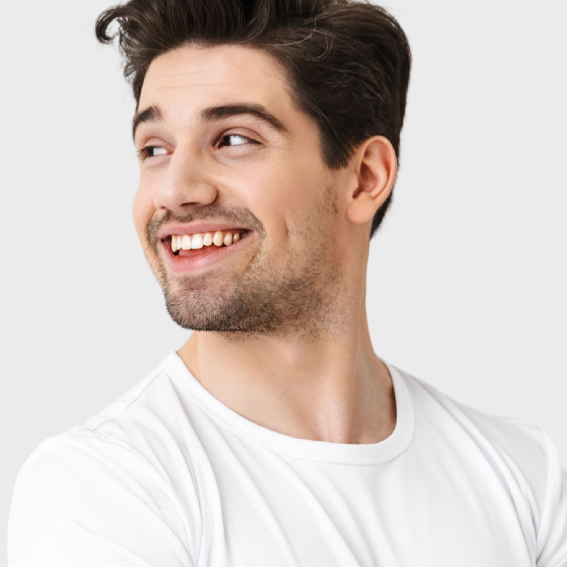 A man in a white t-shirt is smiling and looking to the side