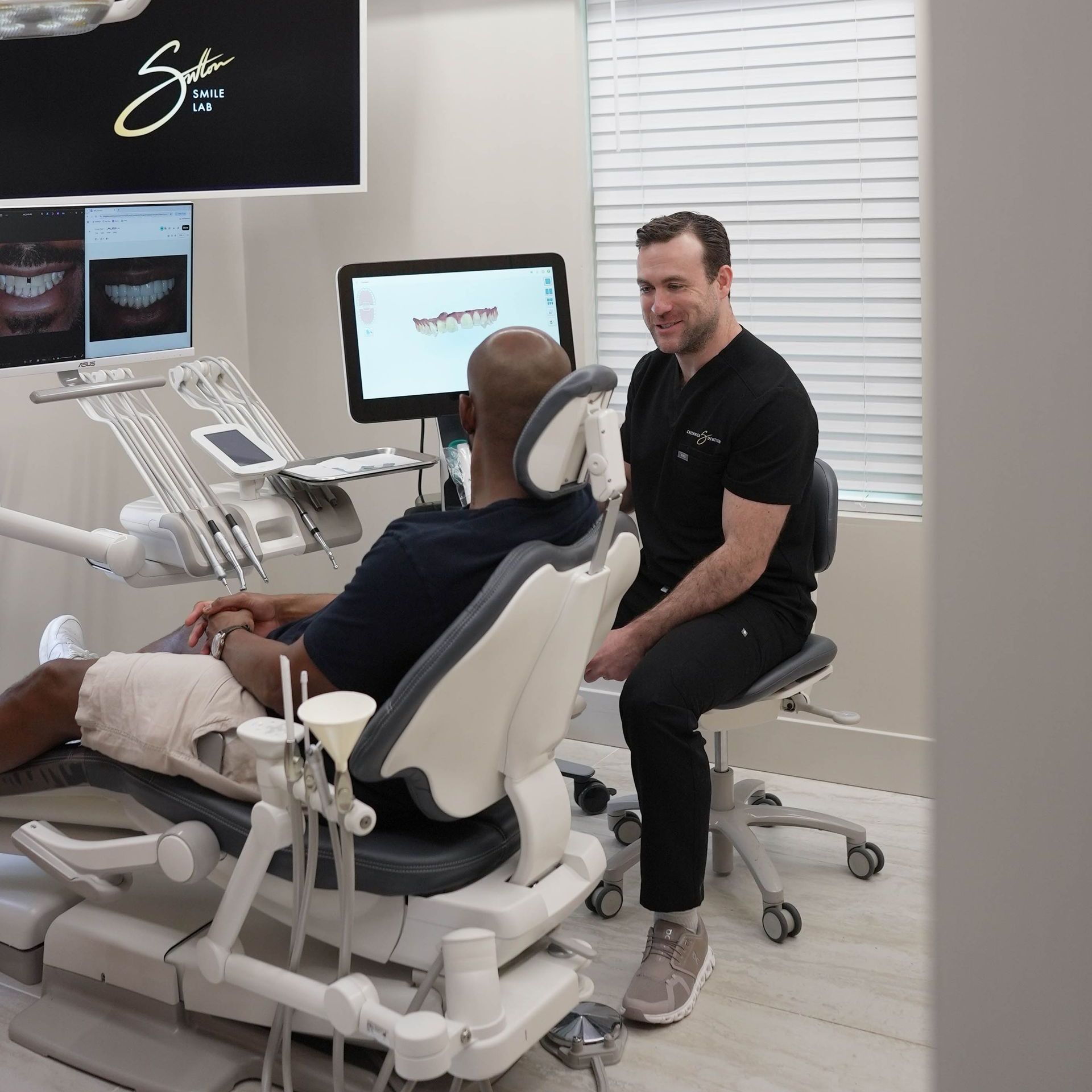 A man is sitting in a dental chair talking to another man