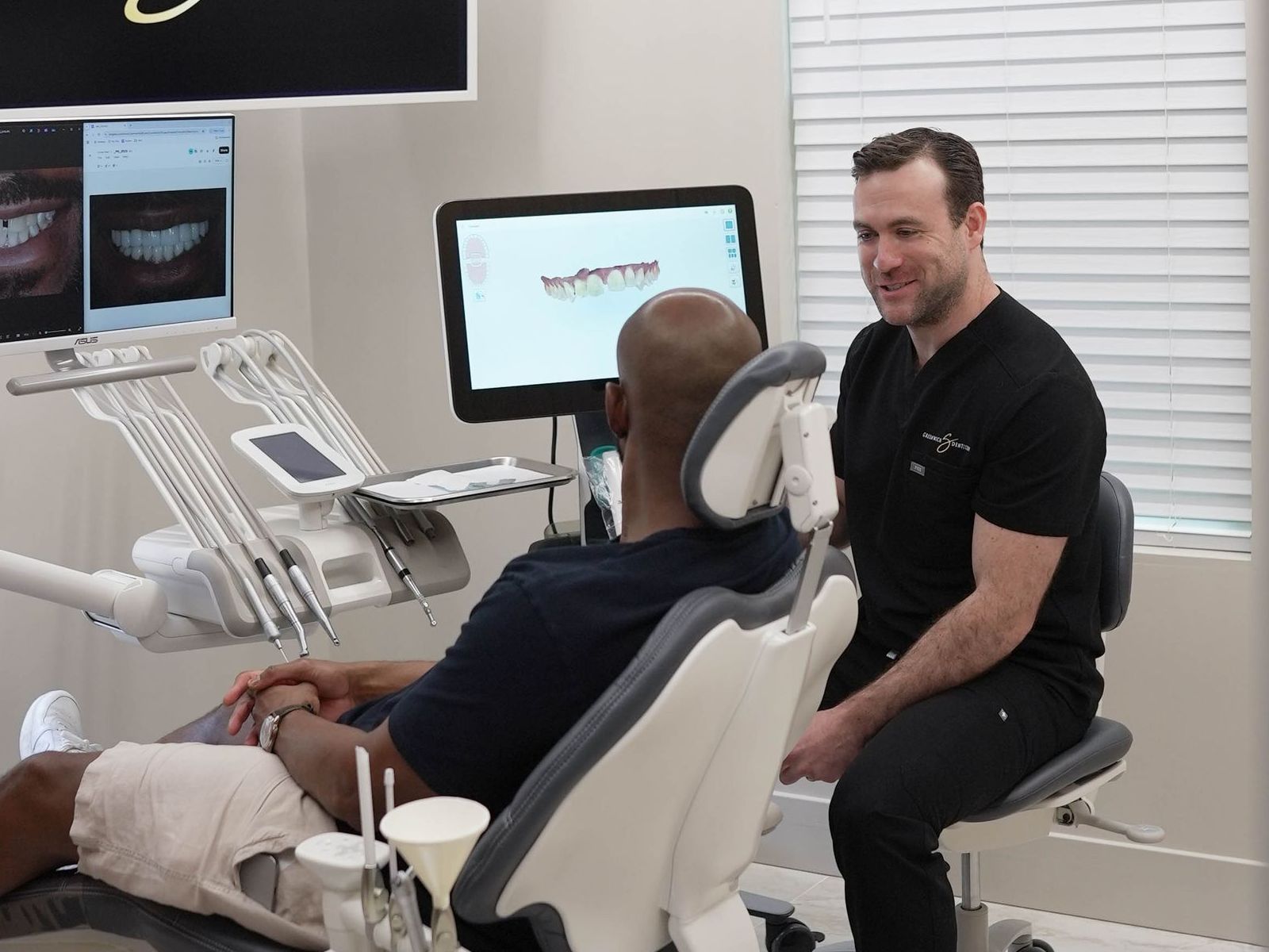 A man is sitting in a dental chair talking to a dentist