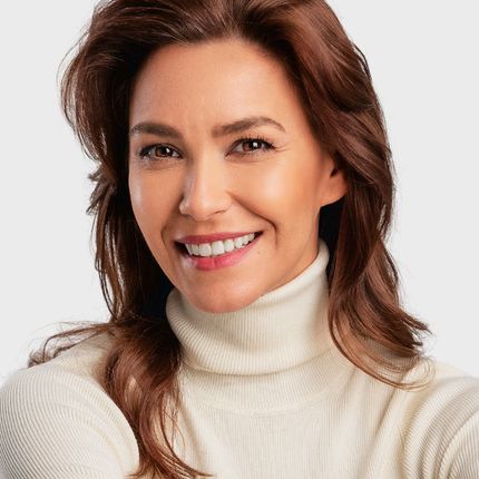 A woman wearing a white turtleneck sweater is smiling