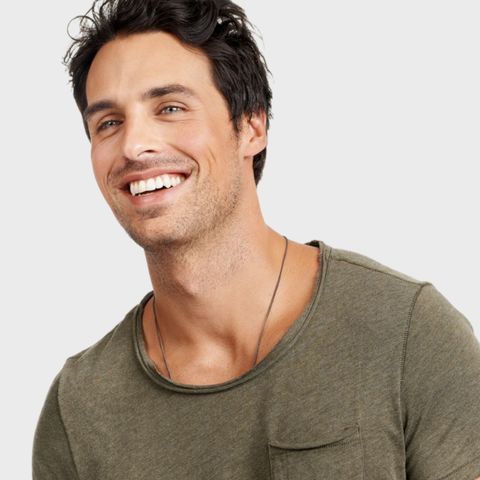 A man wearing a green t-shirt is smiling for the camera