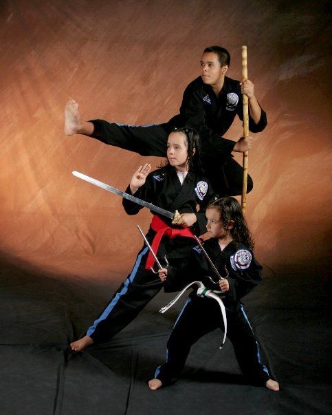 A group of young girls are practicing martial arts with swords and poles