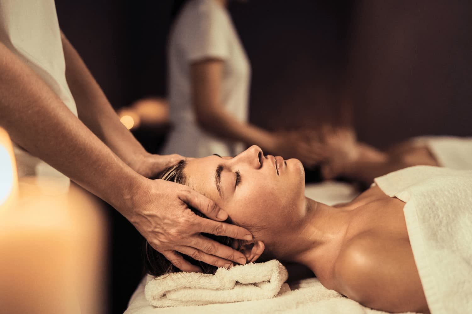 A person receives a relaxing head massage at a spa while lying down with their eyes closed.