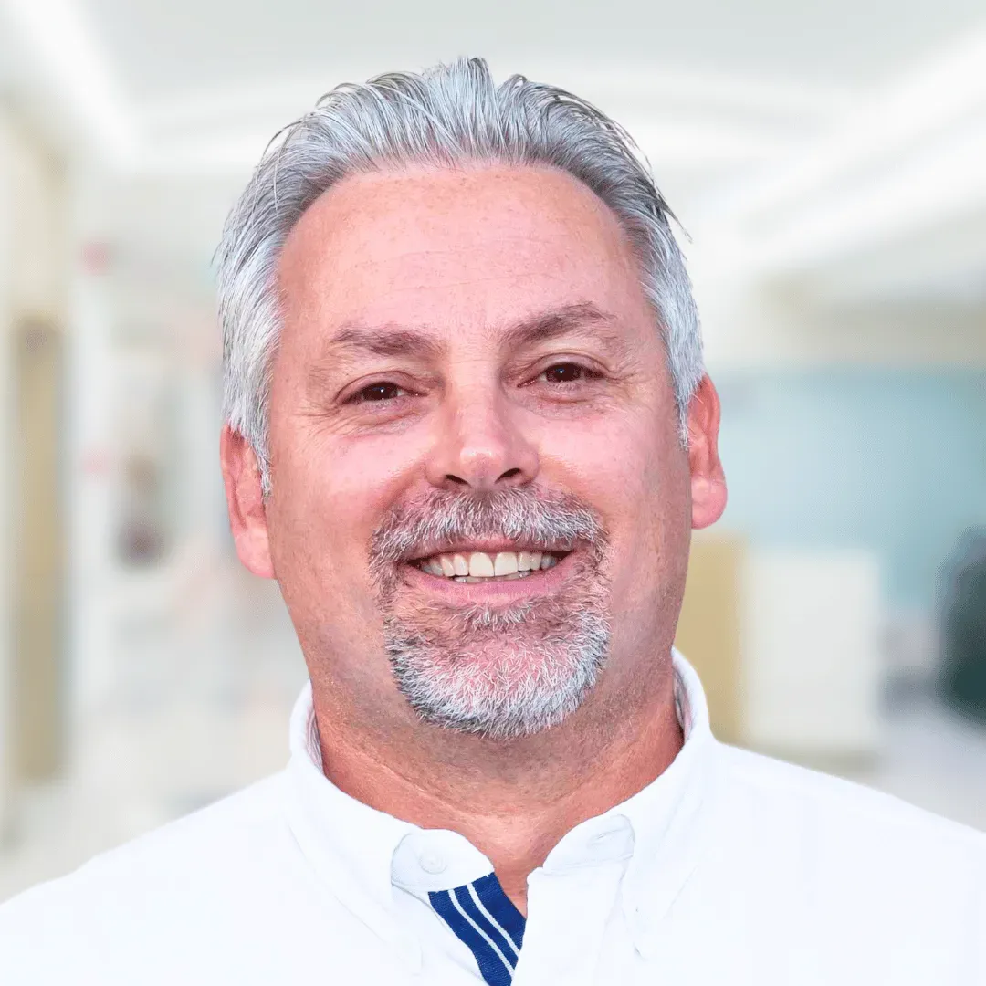 Dr. Glen Mccracken headshot 
A white man with a grey beard wearing a white shirt and tie. 