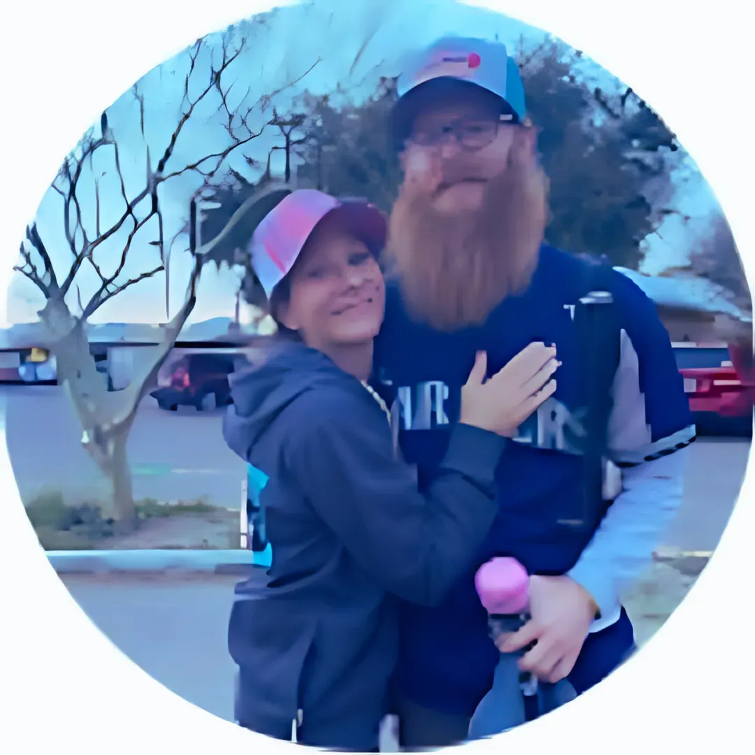 A man and a woman are posing for a picture in a parking lot.