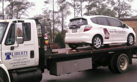 White car being towed by a Liberty tow truck.
