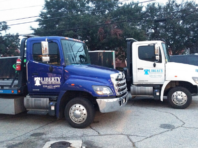 Two Liberty trucks parked side-by-side: blue flatbed and white dump truck.