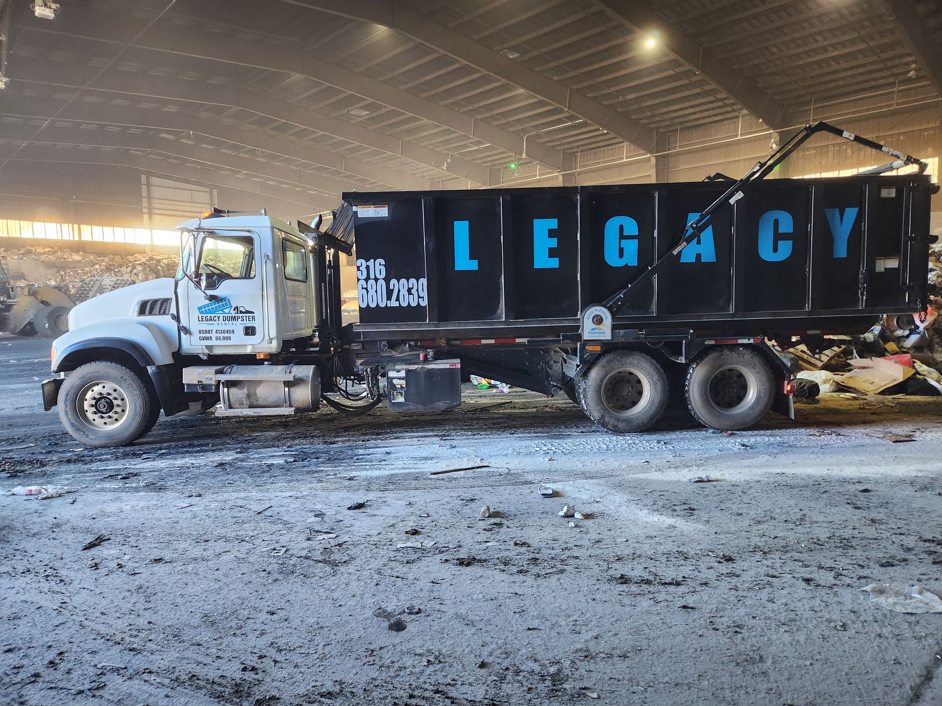 A dump truck with the word legacy on the side is parked in a warehouse.