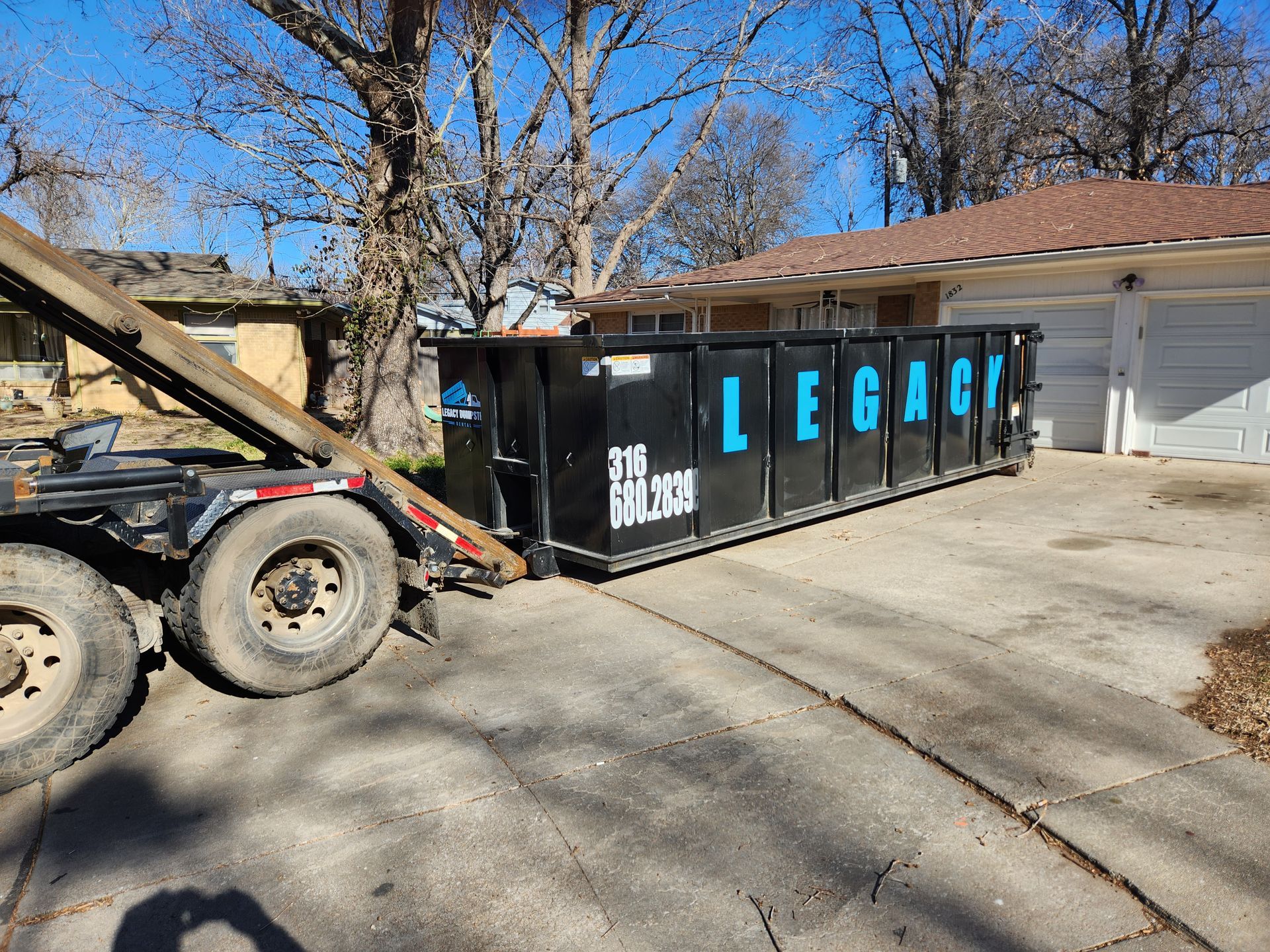 A dumpster is sitting in a driveway next to a house.