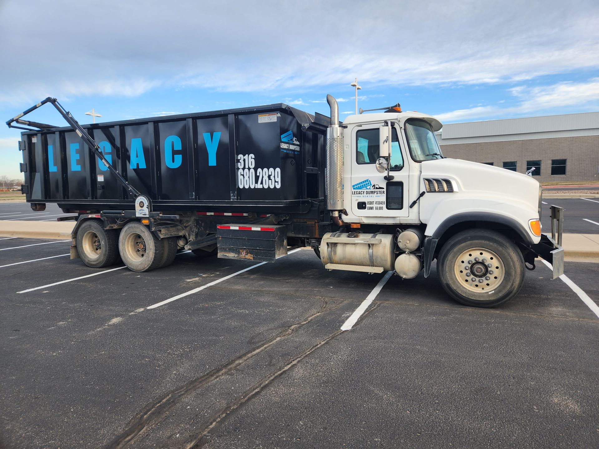 A dump truck is parked in a parking lot with a 30 yard dumpster on the back in wichita