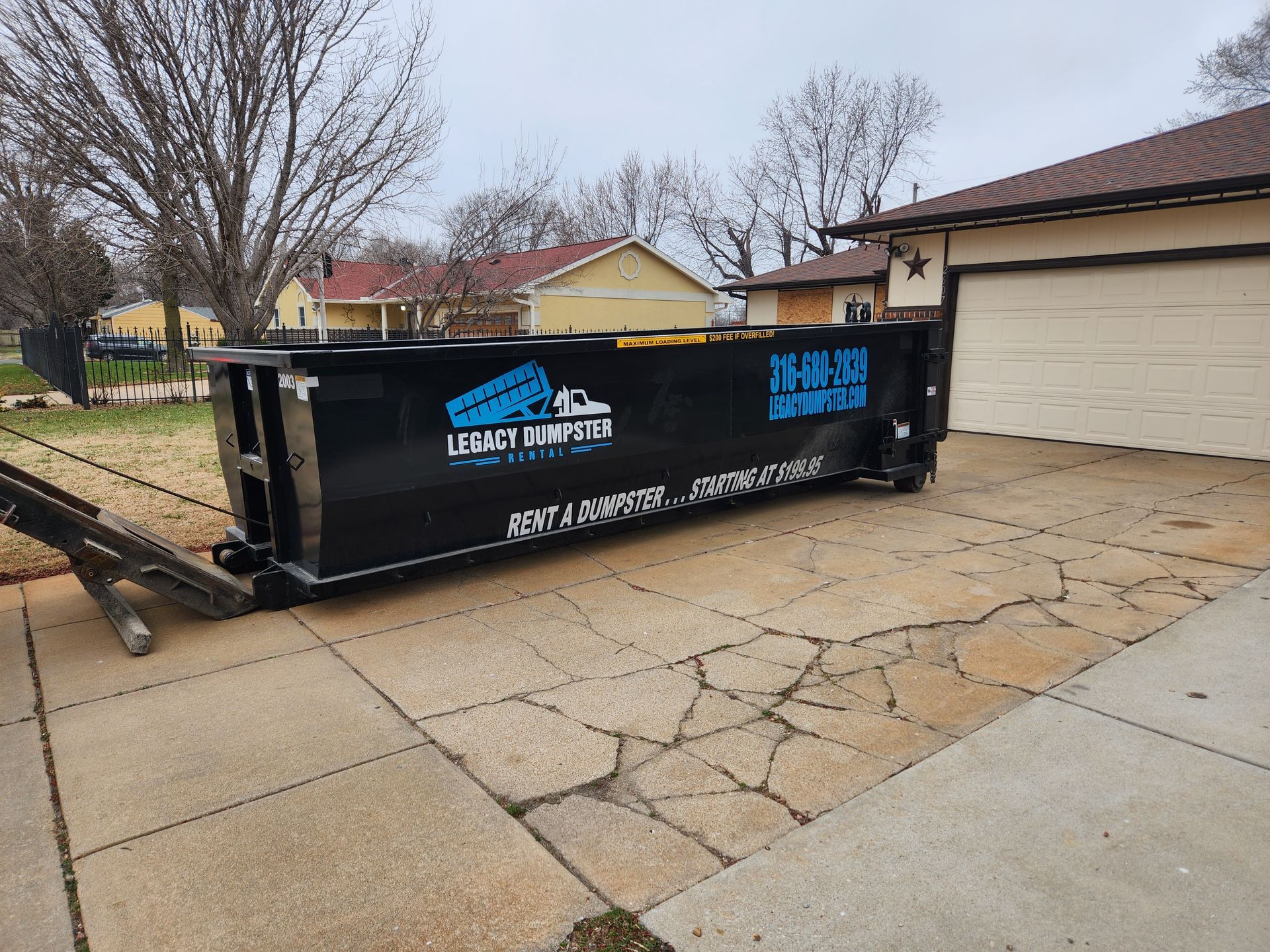 A large dumpster is parked in front of a house.