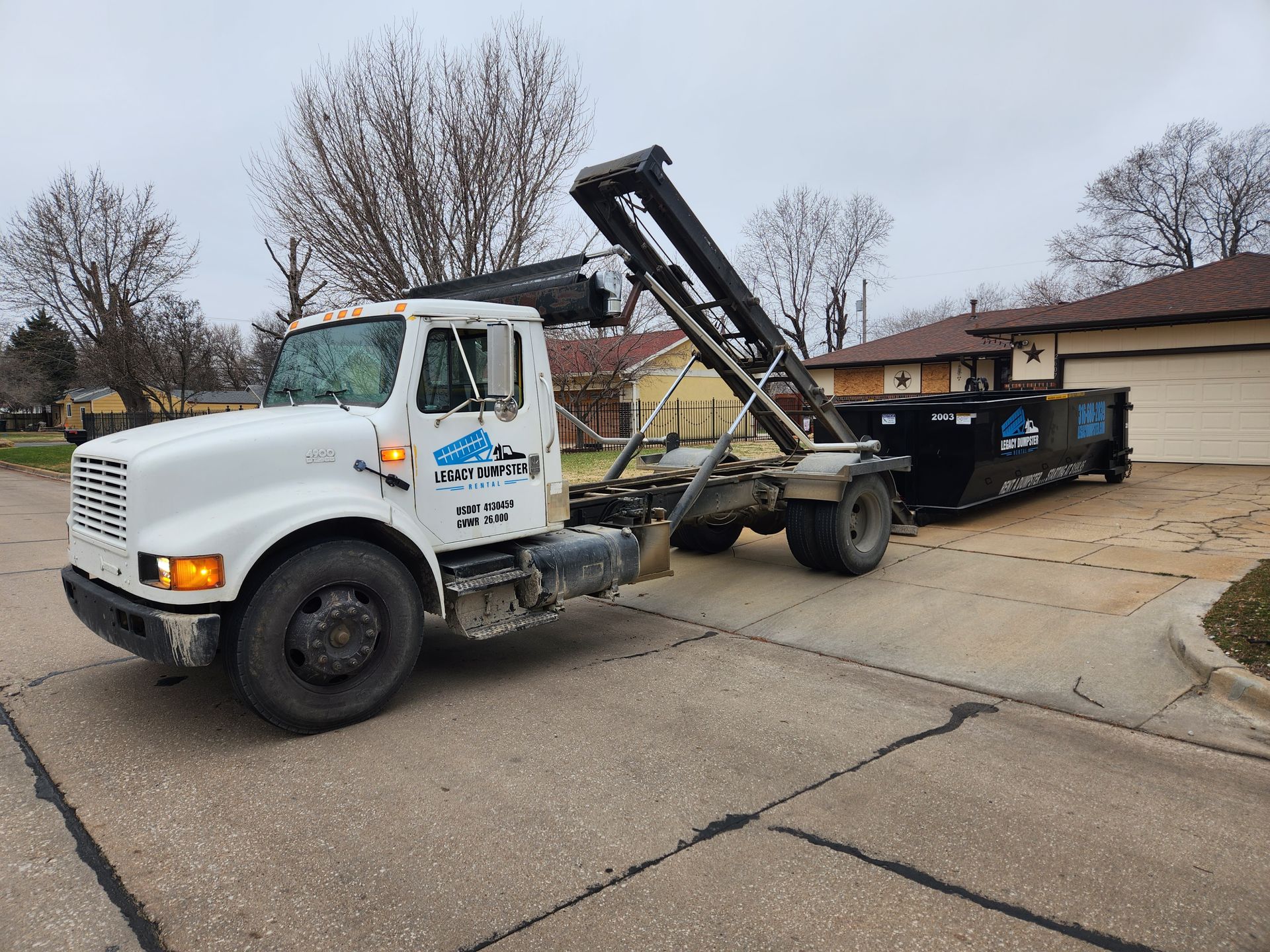 A dump truck is pulling a dumpster down a street.