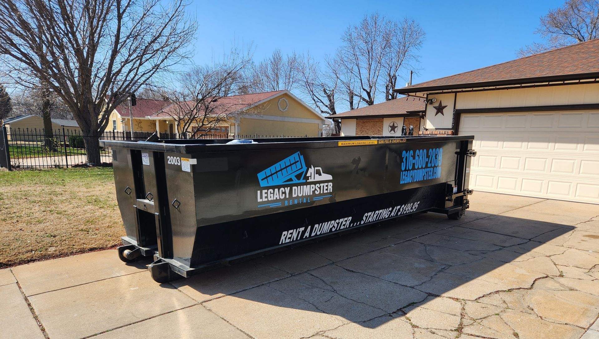 A 20 yard dumpster is parked in front of a house.