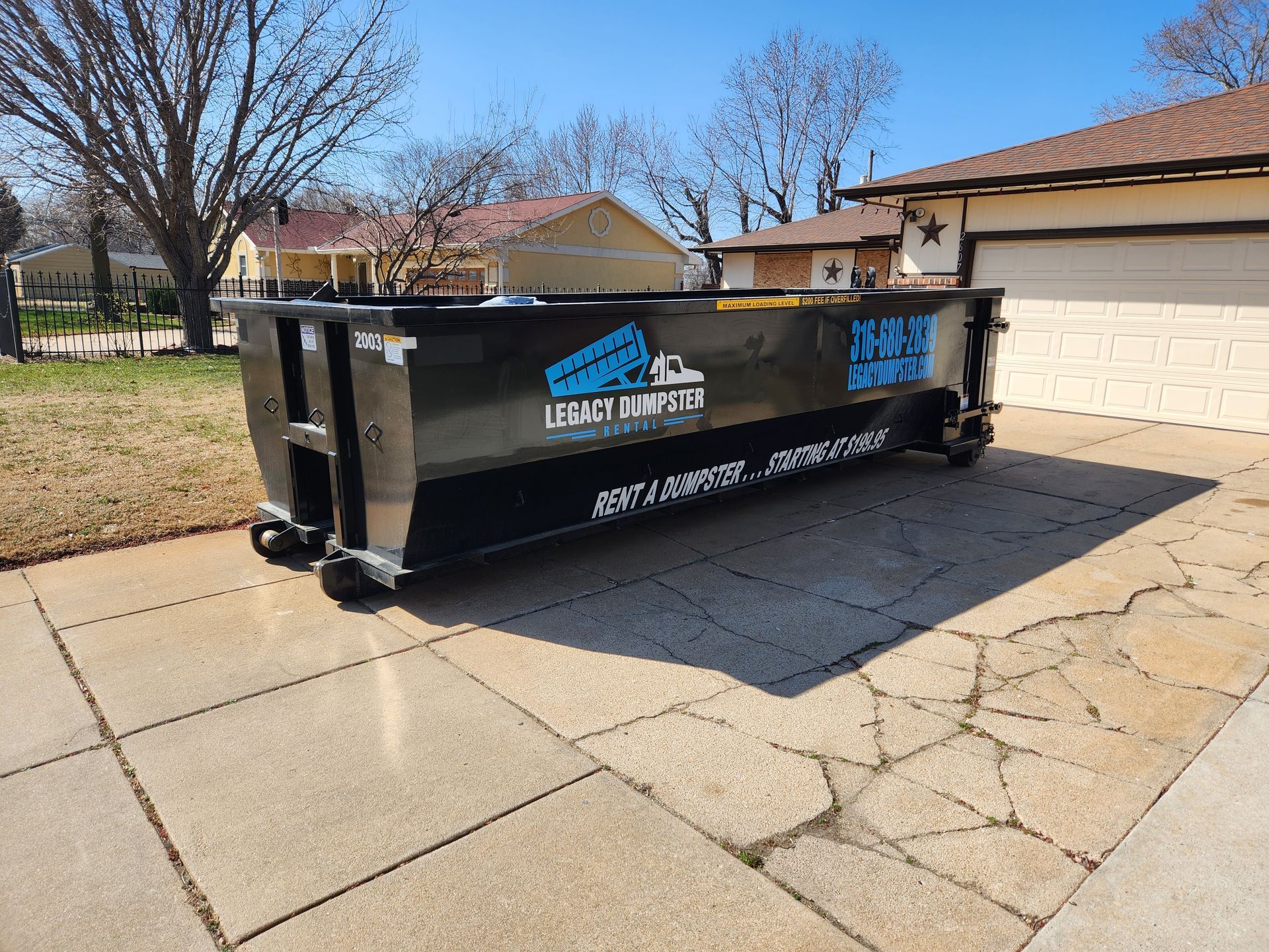 A 20 yard dumpster is parked in front of a house in wichita, KS.